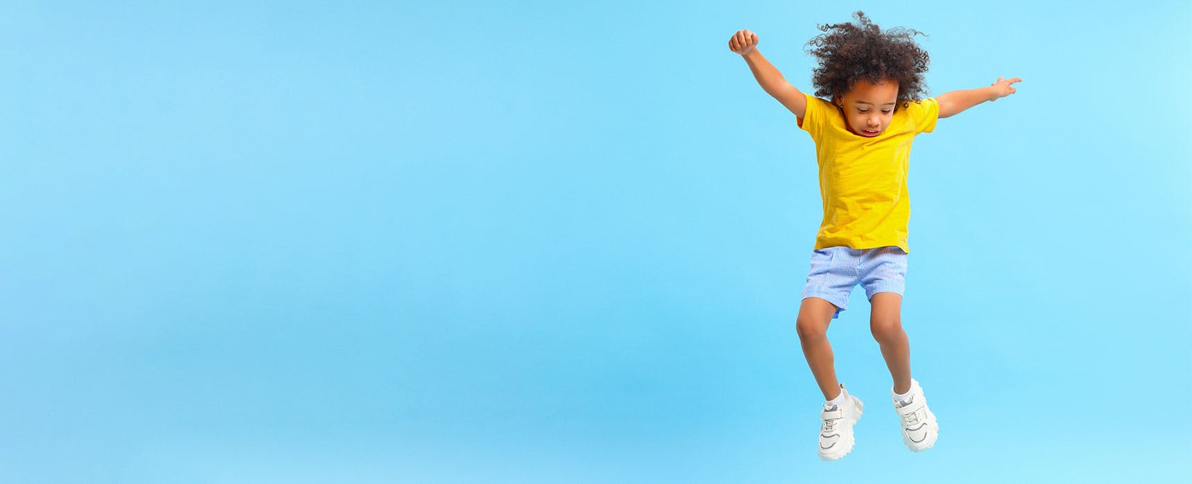 Female child jumping with a bright blue backgorund